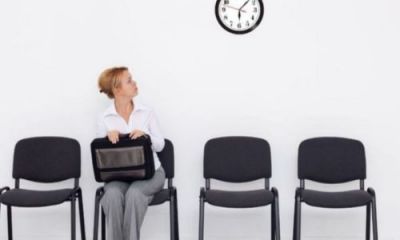 woman sat on chair looking up at wall clock 